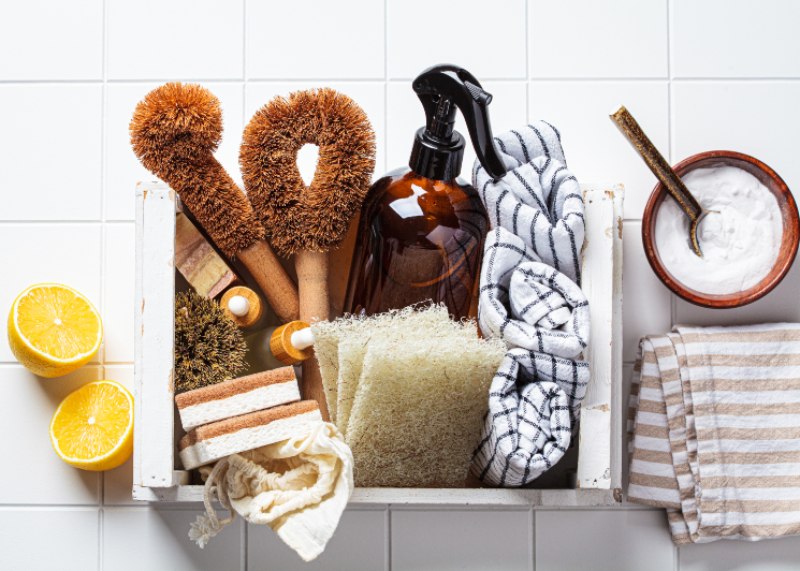 Eco home cleaning accessories. Natural brushes, sponges and organic cleaning products in white wooden box.