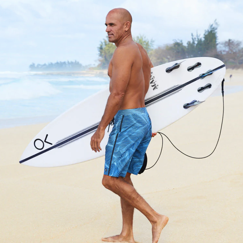 man wearing blue sustainable swimwear on beach by By Kelly Slater