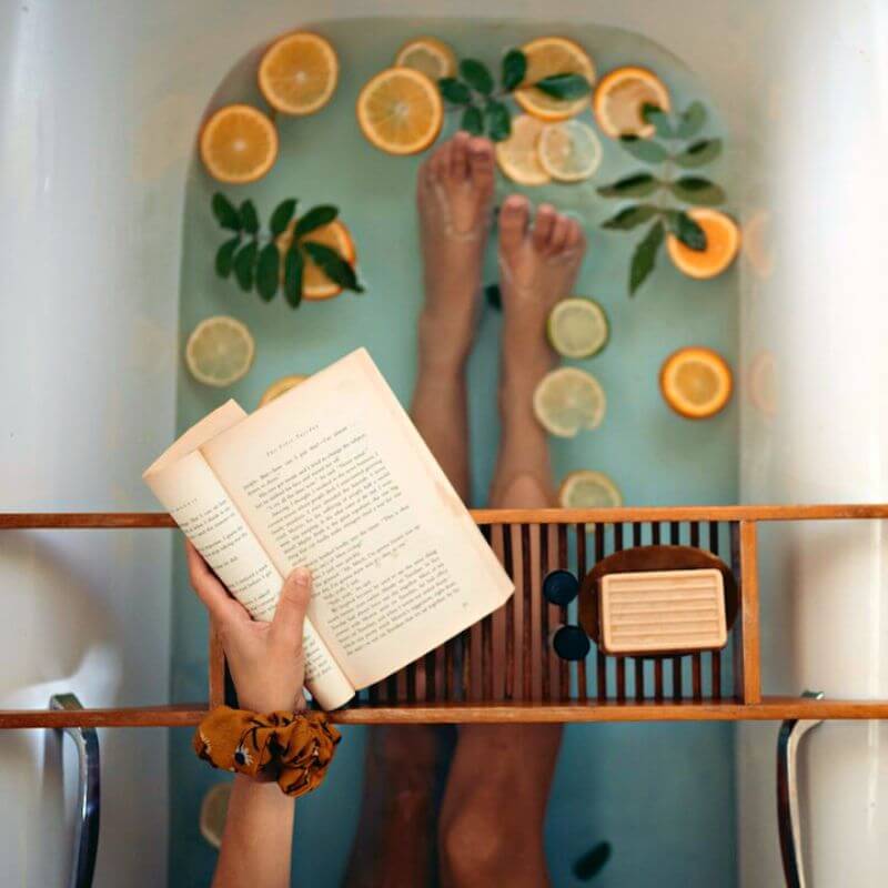 bathtub with citrus and a hand holding a book