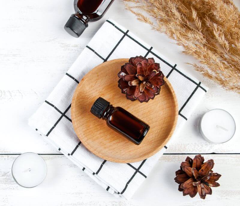 Autumn skin care concept. Bottle of pine essential oil on a white wooden background.