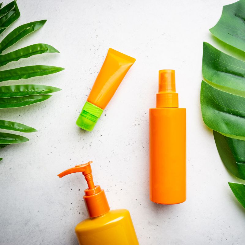 Sunscreen bottles arranged on white background with palm leaves