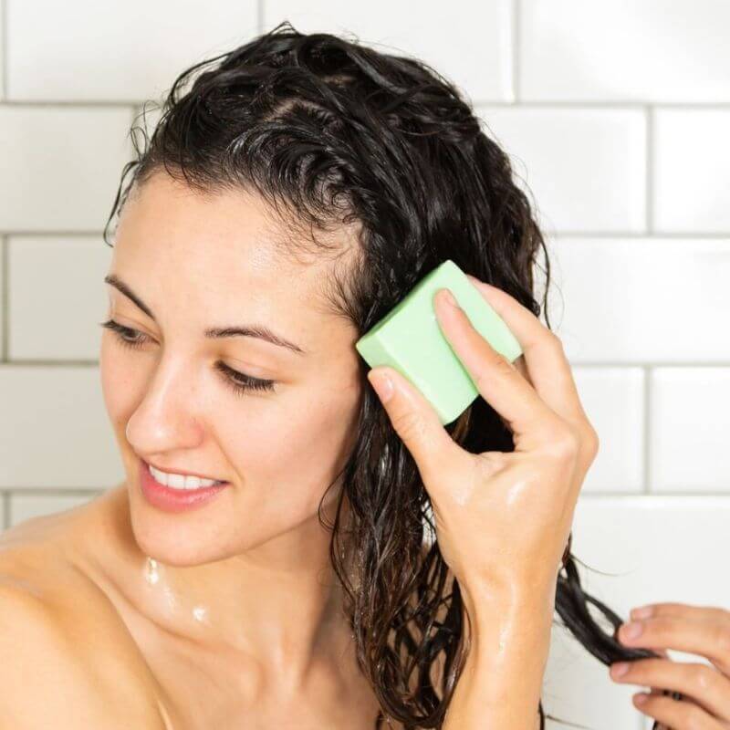 woman using shampoo bar by ethique