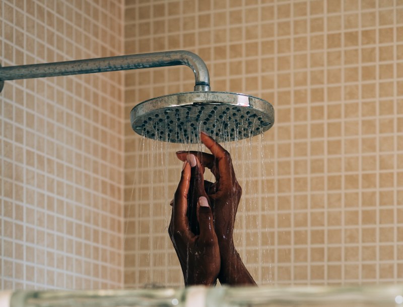 Woman hands taking a showering behind a wall glass