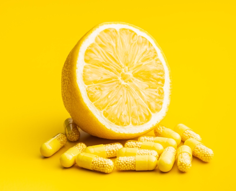 Vitamin capsules. Vitamin C pills and yellow lemon on yellow background.